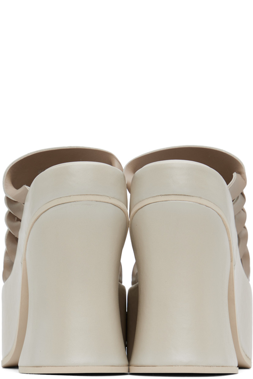 Buffed leather mules in off-white.

· Open square toe
· Twisted detailing and cutouts at sides 
· Logo embossed at padded footbed
· Covered block heel 
· Platform midsole
· Foam rubber sole
· Platform: H2.25" 
· Heel: H5"

Supplier color: Off-white mix