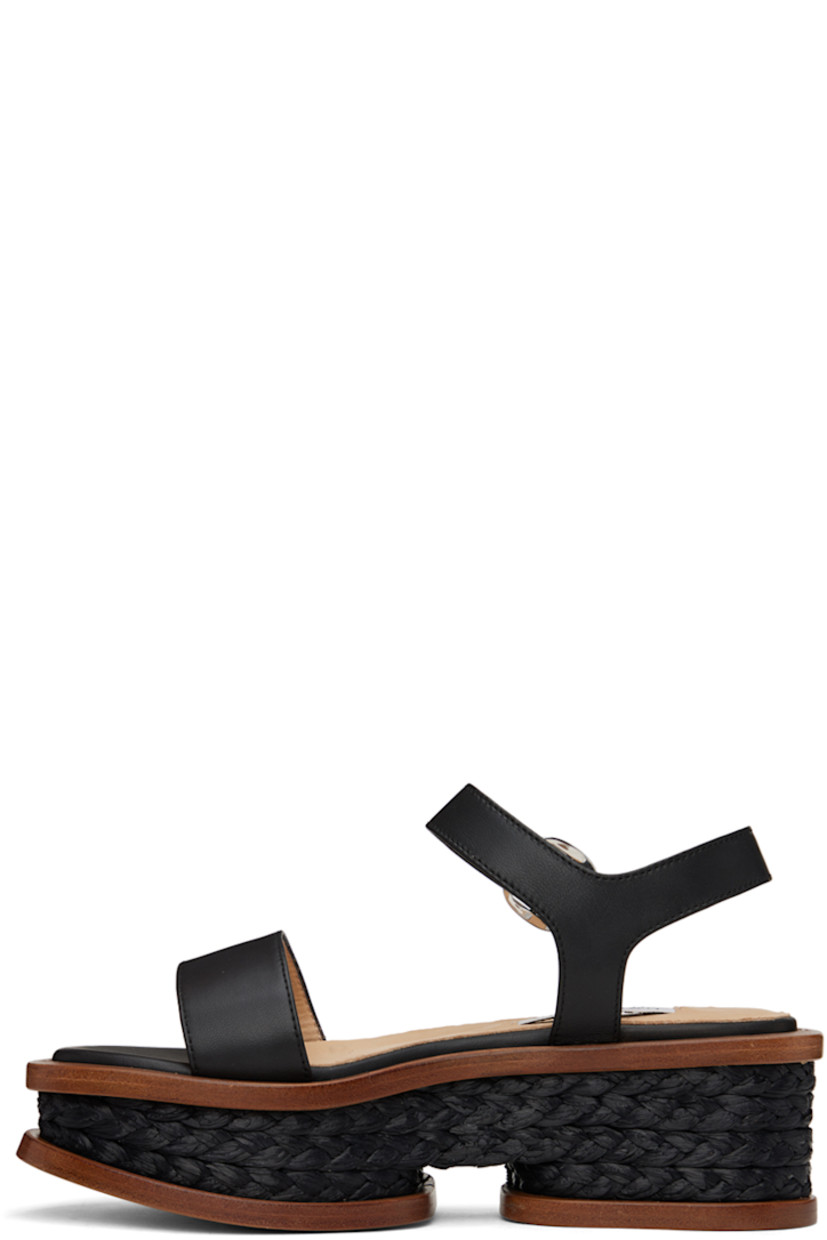 Handcrafted buffed nappa lambskin sandals in black. 

· Hand-woven raffia trim throughout 
· Open pointed toe
· Strap at vamp
· Pin-buckle ankle strap
· Logo patch at padded footbed
· Buffed calfskin lining
· Platform wood midsole 
· Polished leather sole
· Platform: H2.5"

Supplier color: Black