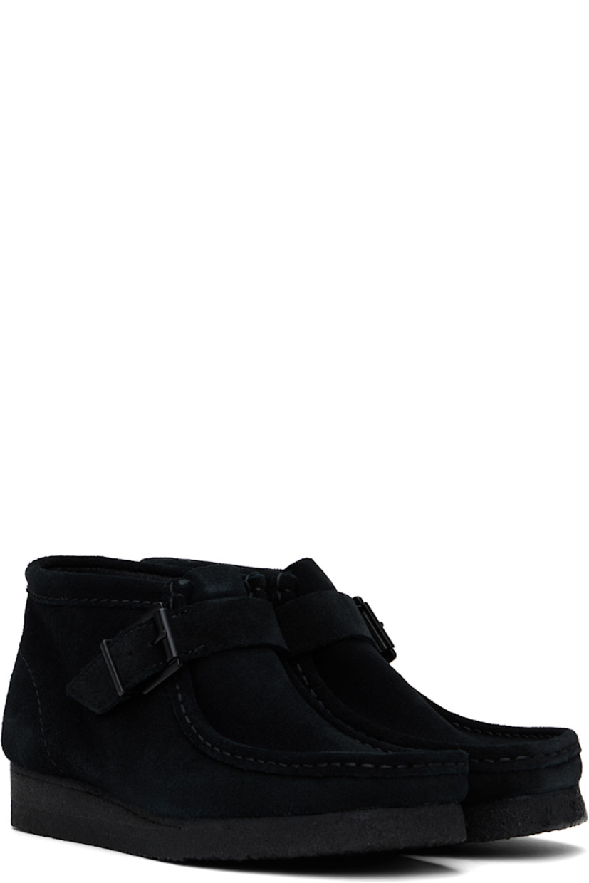 Ankle-high suede boots in black.

· Hand-stitched detailing at square moc toe
· Pin-buckle strap at vamp
· Bellows tongue
· Suede lining
· EVA rubber midsole
· FSC-certified crepe rubber sole

Supplier color: Black suede