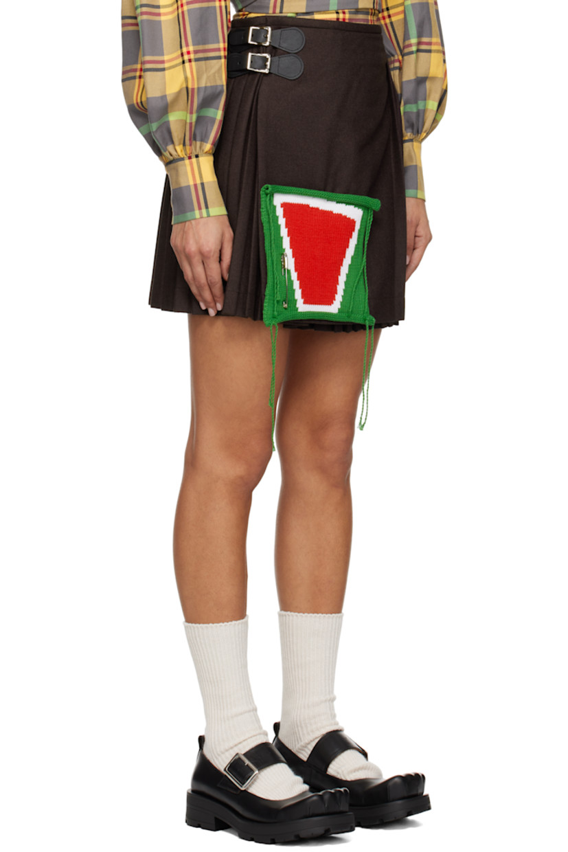 Wool-blend twill miniskirt.

· Pleats throughout
· Wrap construction
· Pin-buckle straps at overlay
· Intarsia-knit panel and safety pin at front

Supplier color: Brown