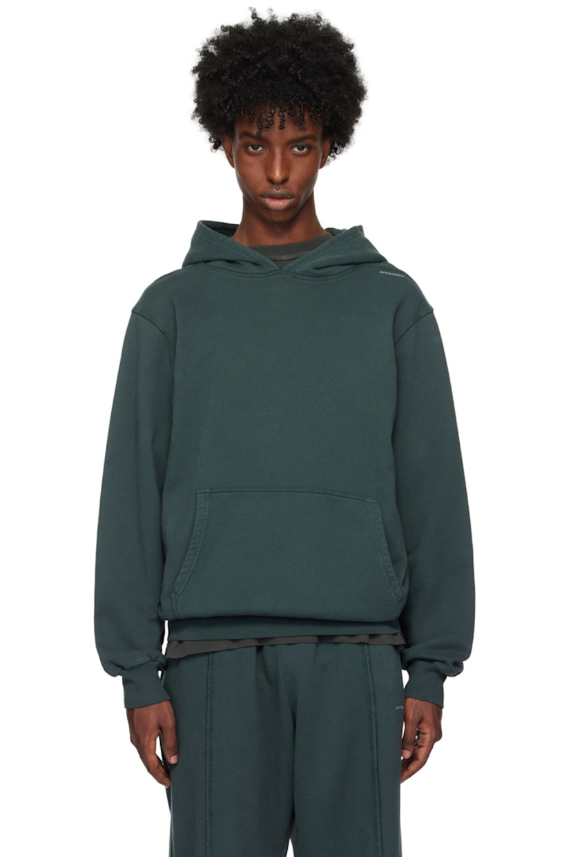Heavyweight cotton fleece hoodie. Garment-dyed. 

· Kangaroo pocket
· Logo printed at shoulder 
· Dropped shoulders

Supplier color: Forest grey