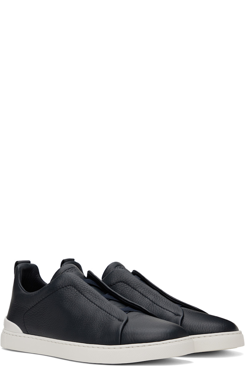 Low-top grained deerskin sneakers in navy.

· Elasticized criss-crossing straps at vamp
· Logo embossed at padded tongue
· Padded collar
· Pull-loop at heel tab
· Rubberized logo patch at heel counter
· Removable cushioned Sanitized® insole
· Buffed leather lining
· Treaded rubber sole

Supplier color: Navy blue