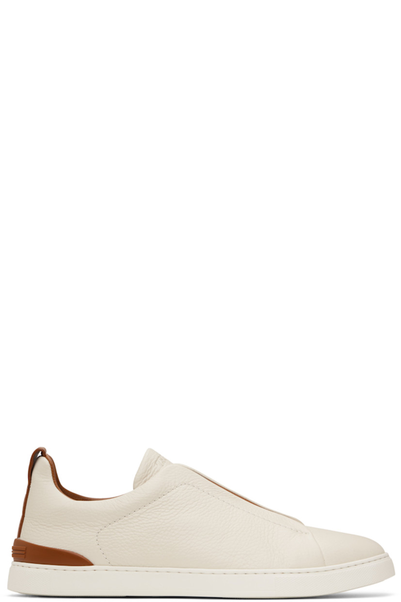 Low-top grained deerskin sneakers in off-white.

· Elasticized criss-crossing straps at vamp
· Logo embossed at padded tongue
· Padded collar
· Pull-loop at heel tab
· Rubberized logo patch at heel counter
· Removable cushioned Sanitized® insole
· Buffed leather lining
· Treaded rubber sole

Supplier color: Pumice white