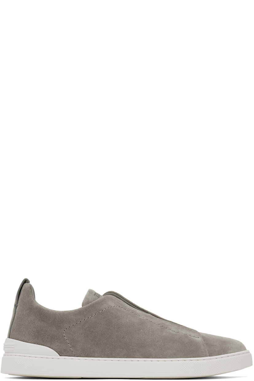 Low-top suede sneakers in gray.

· Elasticized criss-crossing straps at vamp
· Logo embossed at padded tongue
· Padded collar
· Pull-loop at heel tab
· Rubberized logo patch at heel counter
· Removable cushioned Sanitized® insole
· Buffed leather lining
· Treaded rubber sole

Supplier color: Grey melange