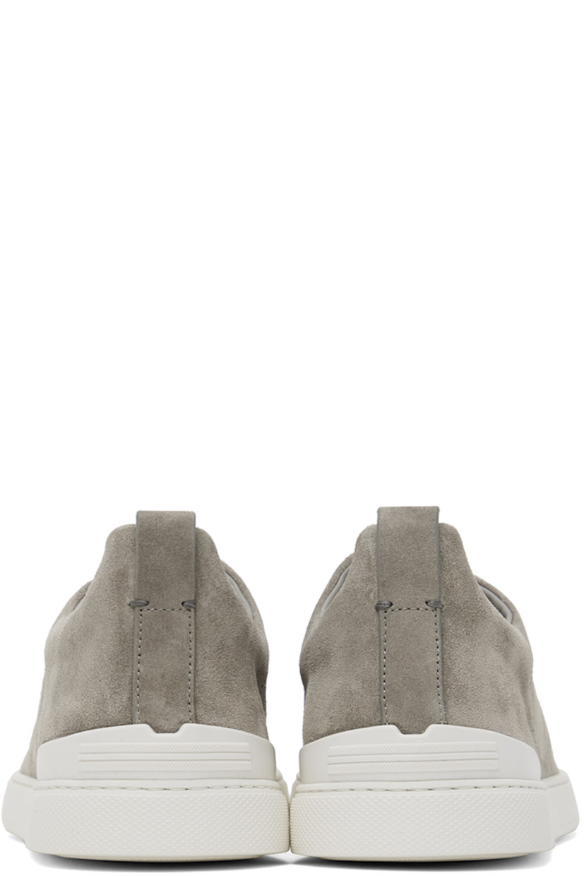 Low-top suede sneakers in gray.

· Elasticized criss-crossing straps at vamp
· Logo embossed at padded tongue
· Padded collar
· Pull-loop at heel tab
· Rubberized logo patch at heel counter
· Removable cushioned Sanitized® insole
· Buffed leather lining
· Treaded rubber sole

Supplier color: Grey melange