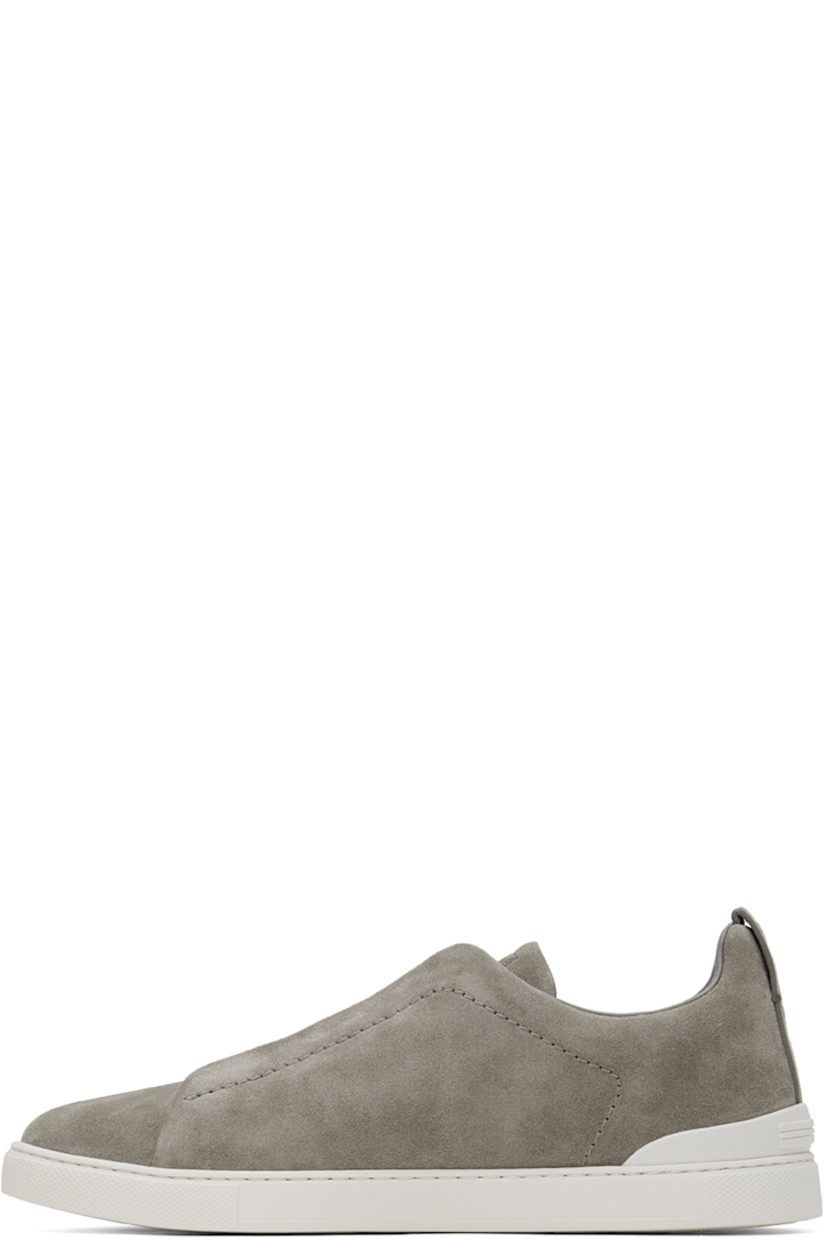 Low-top suede sneakers in gray.

· Elasticized criss-crossing straps at vamp
· Logo embossed at padded tongue
· Padded collar
· Pull-loop at heel tab
· Rubberized logo patch at heel counter
· Removable cushioned Sanitized® insole
· Buffed leather lining
· Treaded rubber sole

Supplier color: Grey melange