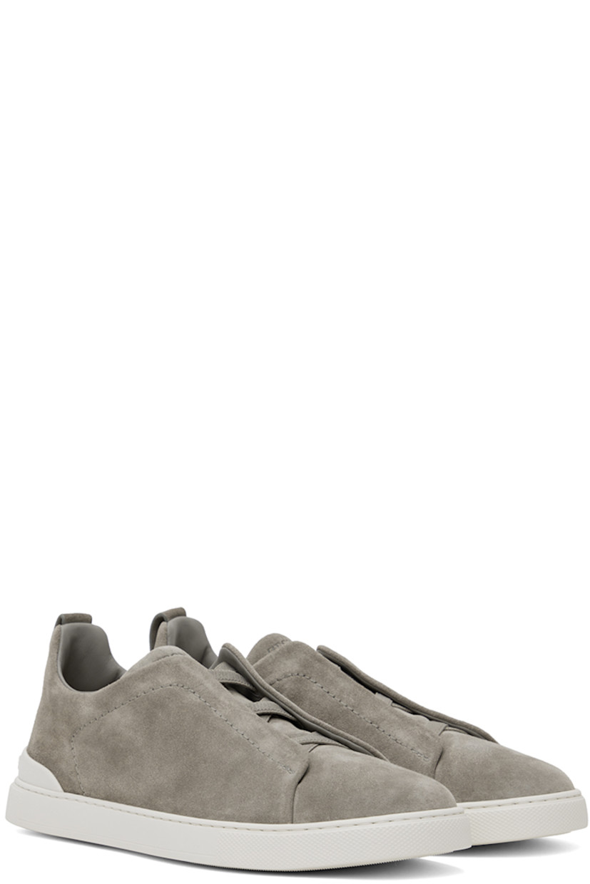 Low-top suede sneakers in gray.

· Elasticized criss-crossing straps at vamp
· Logo embossed at padded tongue
· Padded collar
· Pull-loop at heel tab
· Rubberized logo patch at heel counter
· Removable cushioned Sanitized® insole
· Buffed leather lining
· Treaded rubber sole

Supplier color: Grey melange