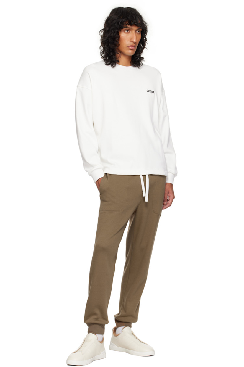 Low-top grained deerskin sneakers in off-white.

· Elasticized criss-crossing straps at vamp
· Logo embossed at padded tongue
· Padded collar
· Pull-loop at heel tab
· Logo embossed at heel counter
· Removable cushioned Sanitized® insole
· Shearling lining
· Treaded rubber sole

Supplier color: White