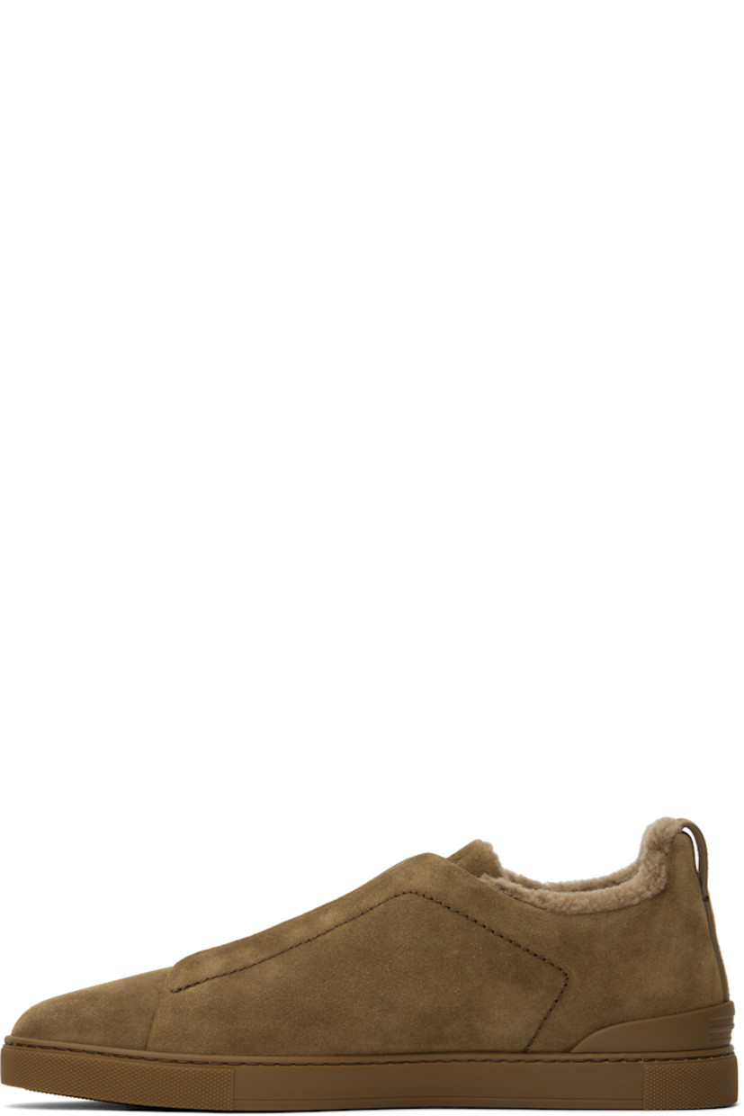 Low-top suede sneakers in brown.

· Elasticized criss-crossing straps at vamp
· Logo embossed at padded tongue
· Padded collar
· Pull-loop at heel tab
· Logo embossed at heel counter
· Removable cushioned Sanitized® insole
· Shearling lining
· Treaded rubber sole

Supplier color: Brown