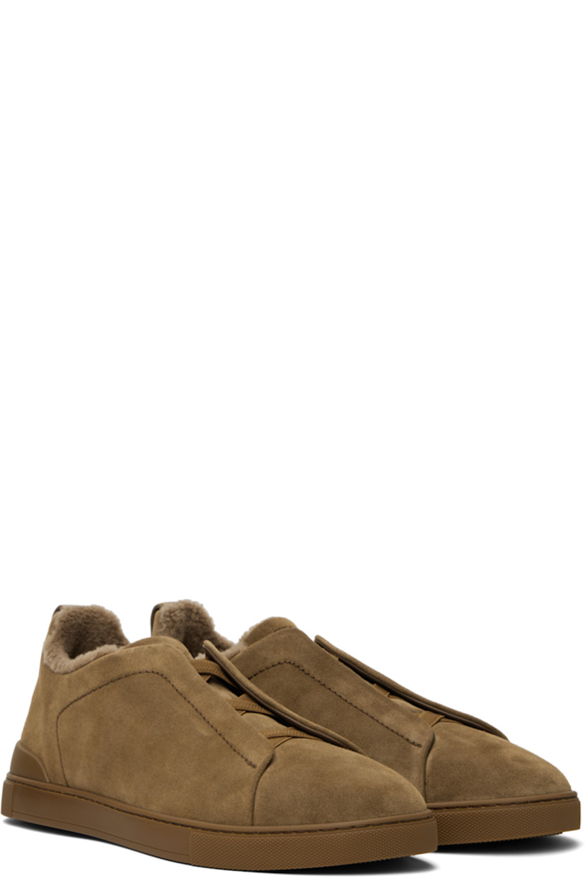 Low-top suede sneakers in brown.

· Elasticized criss-crossing straps at vamp
· Logo embossed at padded tongue
· Padded collar
· Pull-loop at heel tab
· Logo embossed at heel counter
· Removable cushioned Sanitized® insole
· Shearling lining
· Treaded rubber sole

Supplier color: Brown
