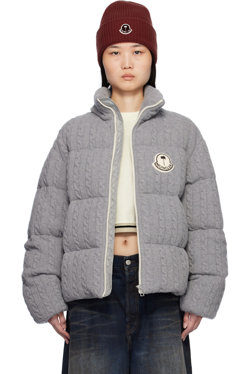 Down-filled and quilted cable knit virgin wool jacket.

· DIST-certified down
· Funnel neck
· Zip closure
· Logo appliqué at chest and back 
· Zip pockets
· Concealed bungee-style drawstring at hem
· Elasticized cuffs
· Full nylon satin lining
· Logo-engraved silver-tone hardware

Part of the Moncler Genius x Palm Angels collaboration.

Supplier color: Gray

Down: 90% down, 10% feather.