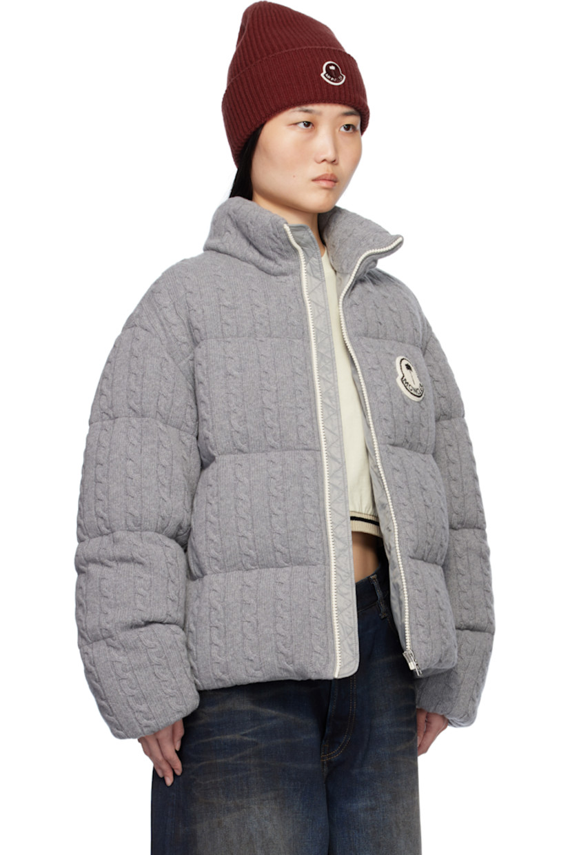 Down-filled and quilted cable knit virgin wool jacket.

· DIST-certified down
· Funnel neck
· Zip closure
· Logo appliqué at chest and back 
· Zip pockets
· Concealed bungee-style drawstring at hem
· Elasticized cuffs
· Full nylon satin lining
· Logo-engraved silver-tone hardware

Part of the Moncler Genius x Palm Angels collaboration.

Supplier color: Gray

Down: 90% down, 10% feather.