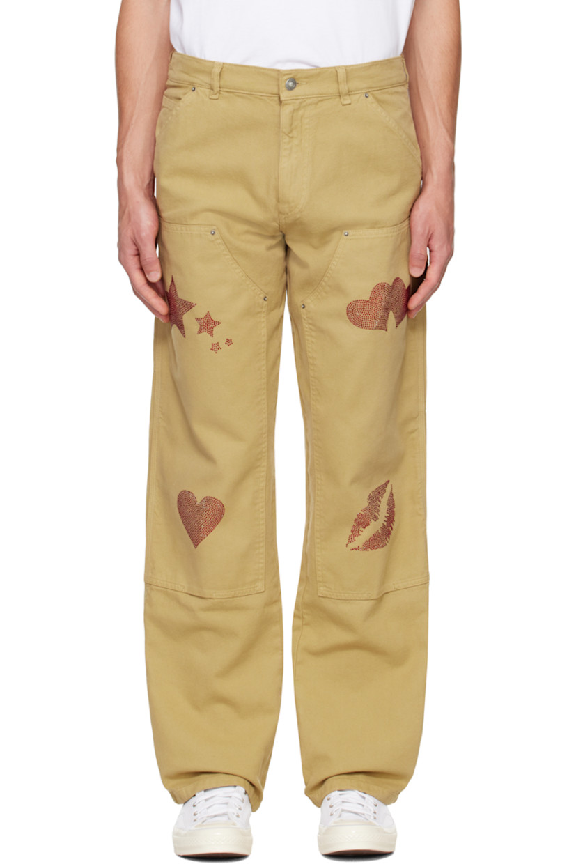 Deadstock cotton canvas trousers. 

· Belt loops
· Five-pocket styling 
· Zip-fly 
· Panel at knees
· Crystal-cut graphics at legs
· Hammer loop at outseam
· Patch pockets at outseams
· Crystal-cut logo graphic at back pocket

Featuring artwork by Vanna Youngstein.

Supplier color: Dark beige