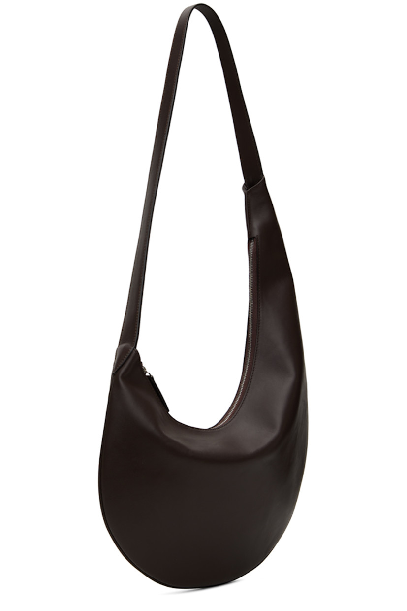 Buffed calfskin shoulder bag in brown. 

· Piping throughout 
· Fixed shoulder strap
· Logo embossed at face
· Zip closure
· Patch pocket at interior 
· Faille lining
· H6.5" x W10" 
· Total height: H26.5"

Supplier color: Dark chocolate