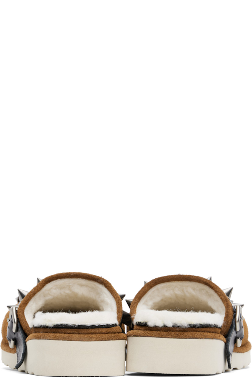 Suede slippers in brown. 

· Graphic hardware at toe
· Studded pin-buckle strap at collar 
· Sherpa fleece lining 
· Foam rubber midsole
· Lugged rubber sole

Supplier color: Camel suede