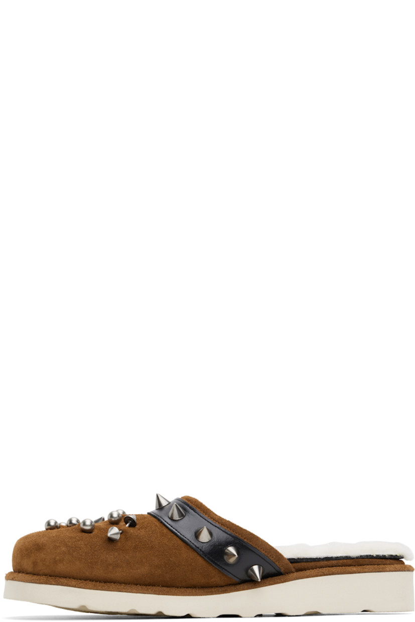 Suede slippers in brown. 

· Graphic hardware at toe
· Studded pin-buckle strap at collar 
· Sherpa fleece lining 
· Foam rubber midsole
· Lugged rubber sole

Supplier color: Camel suede