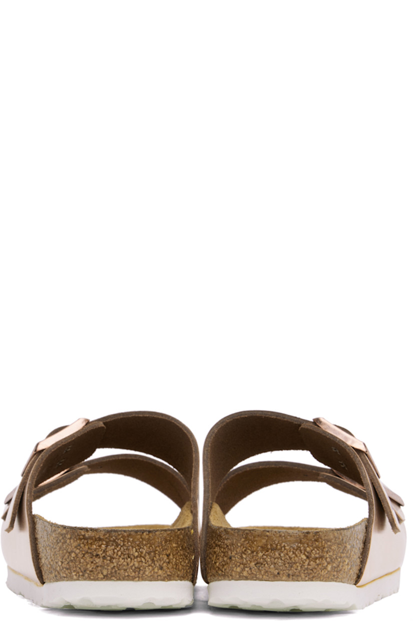 Buffed leather slip-on flat sandals in metallic copper tone.

· Open toe
· Pin-buckle straps at vamp
· Logo embossed at inner side
· Logo printed at cushioned molded suede footbed
· Cork-latex midsole
· Treaded EVA rubber sole
· Logo-engraved antiqued copper-tone hardware

Supplier color: Metallic copper