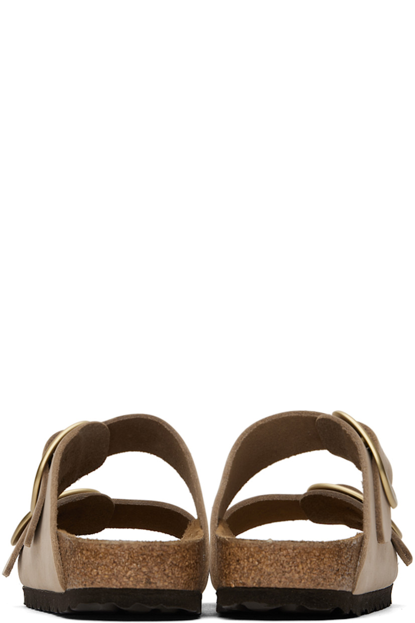 Nubuck slip-on sandals in taupe. 

· Open toe
· Pin-buckle straps at vamp
· Logo embossed at inner side
· Logo stamp at molded suede footbed
· Cork midsole
· Treaded EVA rubber sole
· Logo-engraved gold-tone hardware

Supplier color: Sandcastle