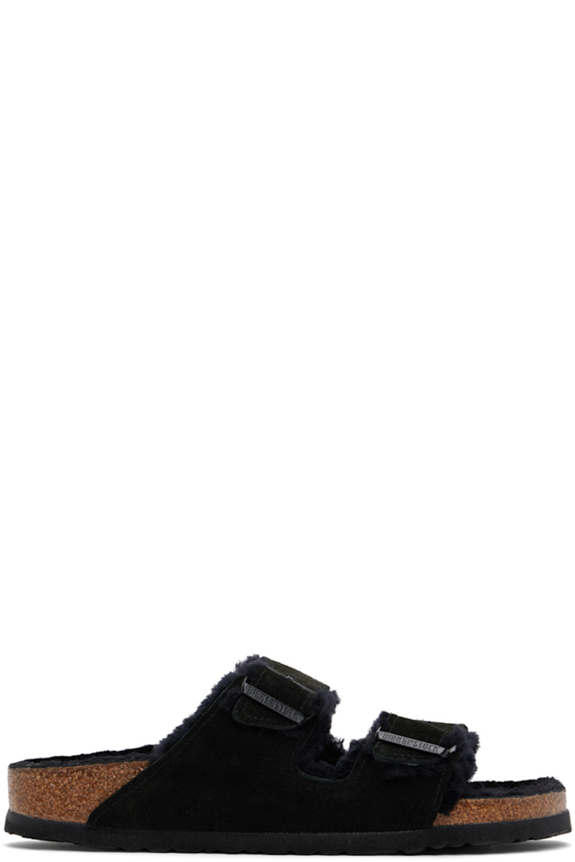Lambskin suede slip-on flat sandals in black.

· Open toe
· Pin-buckle straps at vamp
· Logo embossed at inner side
· Logo patch at molded shearling footbed
· Shearling lining
· Cork-latex midsole
· Treaded EVA rubber sole
· Logo-engraved gunmetal-tone hardware

Supplier color: Black