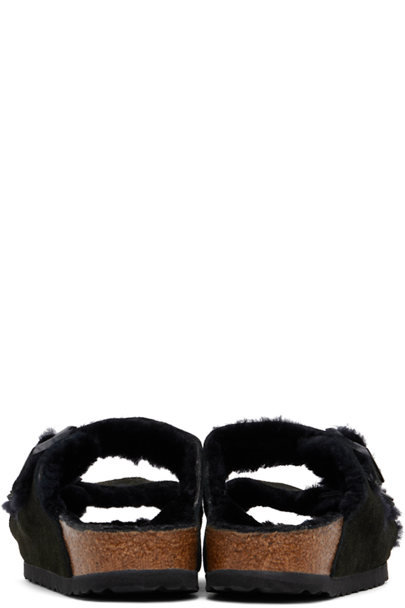 Lambskin suede slip-on flat sandals in black.

· Open toe
· Pin-buckle straps at vamp
· Logo embossed at inner side
· Logo patch at molded shearling footbed
· Shearling lining
· Cork-latex midsole
· Treaded EVA rubber sole
· Logo-engraved gunmetal-tone hardware

Supplier color: Black