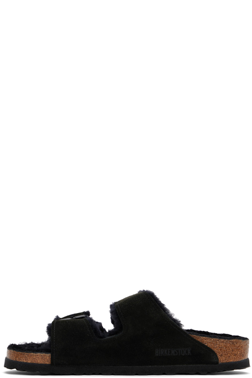 Lambskin suede slip-on flat sandals in black.

· Open toe
· Pin-buckle straps at vamp
· Logo embossed at inner side
· Logo patch at molded shearling footbed
· Shearling lining
· Cork-latex midsole
· Treaded EVA rubber sole
· Logo-engraved gunmetal-tone hardware

Supplier color: Black
