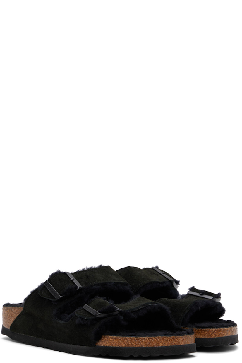 Lambskin suede slip-on flat sandals in black.

· Open toe
· Pin-buckle straps at vamp
· Logo embossed at inner side
· Logo patch at molded shearling footbed
· Shearling lining
· Cork-latex midsole
· Treaded EVA rubber sole
· Logo-engraved gunmetal-tone hardware

Supplier color: Black