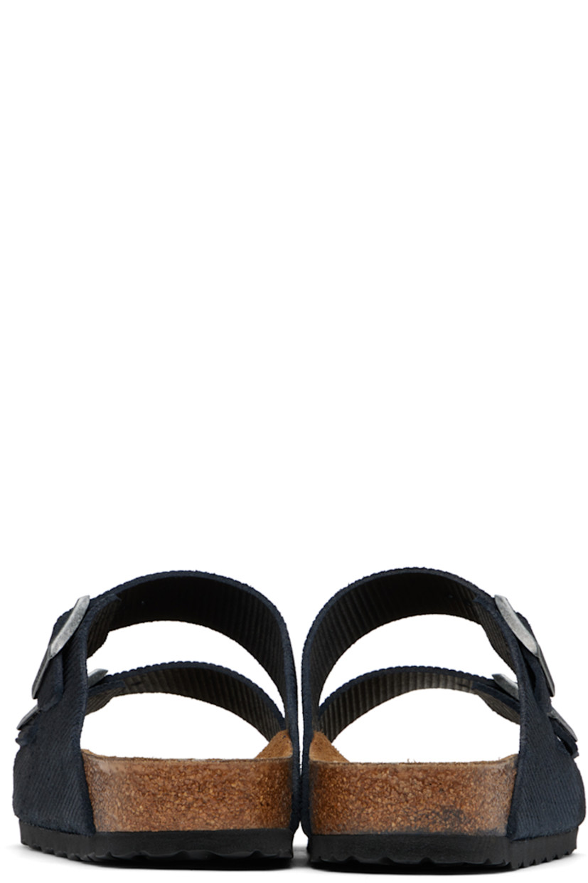 Corduroy-embossed suede slip-on sandals in navy.

· Open toe
· Adjustable pin-buckle straps at vamp
· Logo embossed at inner side
· Logo stamp at molded suede footbed
· Cork midsole
· Treaded EVA rubber sole
· Logo-engraved antiqued gold-tone hardware

Supplier color: Midnight corduroy