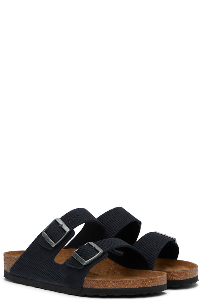 Corduroy-embossed suede slip-on sandals in navy.

· Open toe
· Adjustable pin-buckle straps at vamp
· Logo embossed at inner side
· Logo stamp at molded suede footbed
· Cork midsole
· Treaded EVA rubber sole
· Logo-engraved antiqued gold-tone hardware

Supplier color: Midnight corduroy