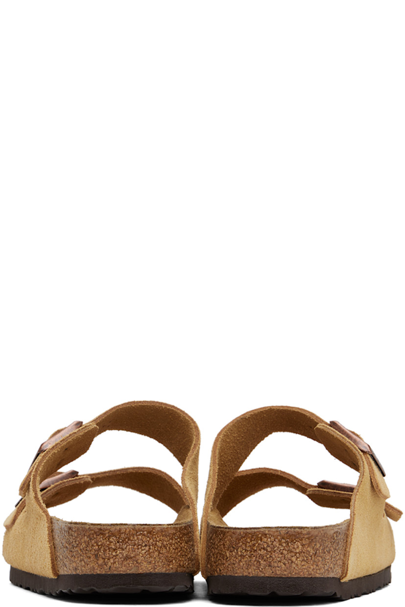 Suede slip-on sandals in beige. 

· Open toe
· Adjustable pin-buckle straps at vamp
· Logo embossed at inner side
· Logo stamp at molded suede footbed
· Cork midsole
· Treaded EVA rubber sole
· Logo-engraved copper-tone hardware

Supplier color: Latte cream suede