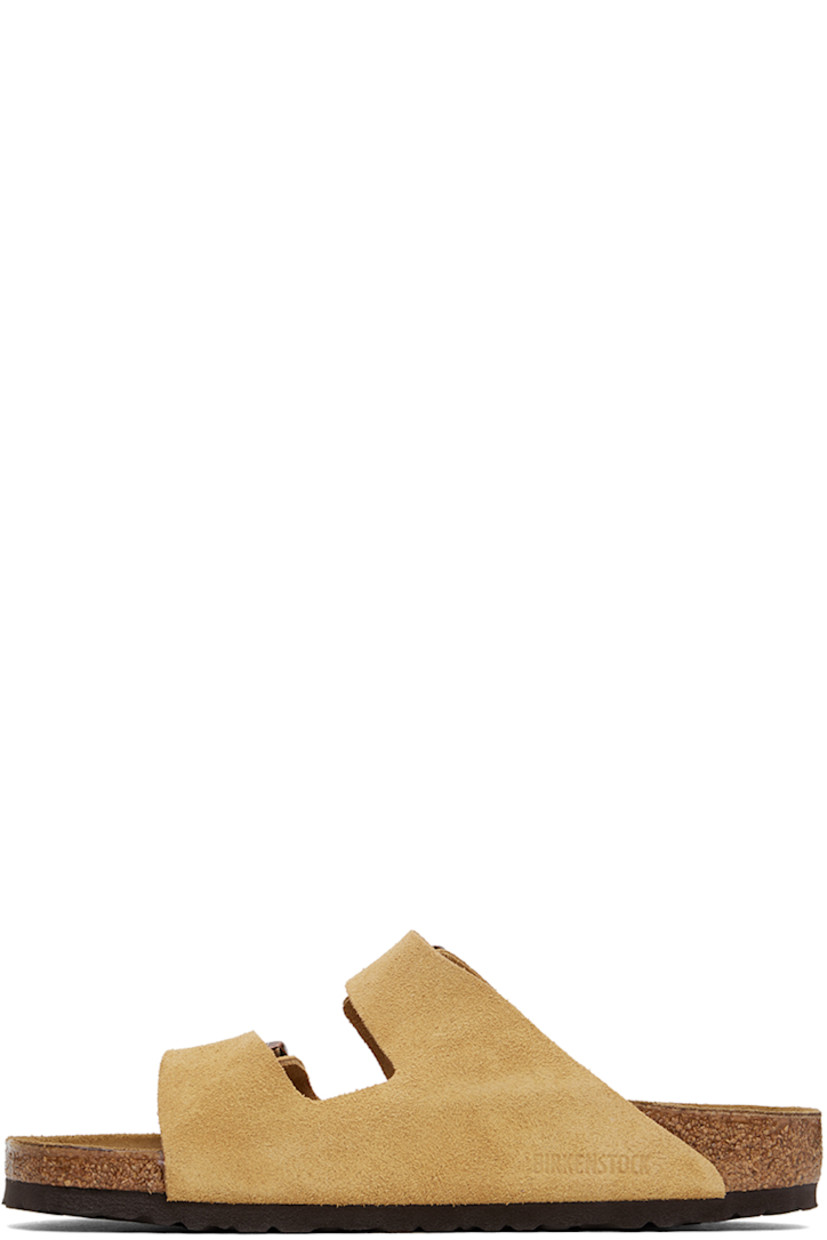 Suede slip-on sandals in beige. 

· Open toe
· Adjustable pin-buckle straps at vamp
· Logo embossed at inner side
· Logo stamp at molded suede footbed
· Cork midsole
· Treaded EVA rubber sole
· Logo-engraved copper-tone hardware

Supplier color: Latte cream suede
