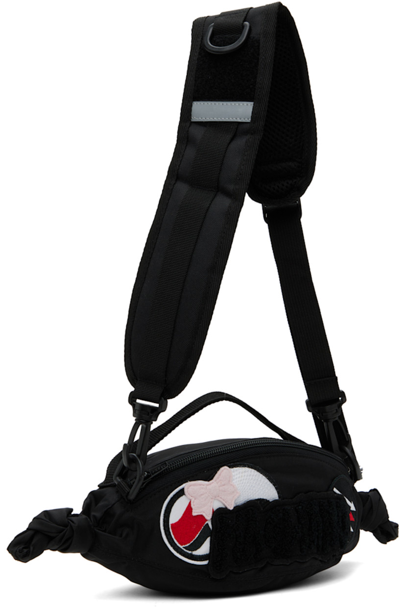 Canvas messenger bag in black.

· Webbing carry handle
· Padded detachable and adjustable shoulder strap
· D-ring and daisy chain at shoulder strap
· Graphic appliqués at face
· Bouclé logo appliqué at face 
· Knotted accent at sides
· Zip closure
· Canvas lining
· H4" x W11" x D4"

Supplier color: Black