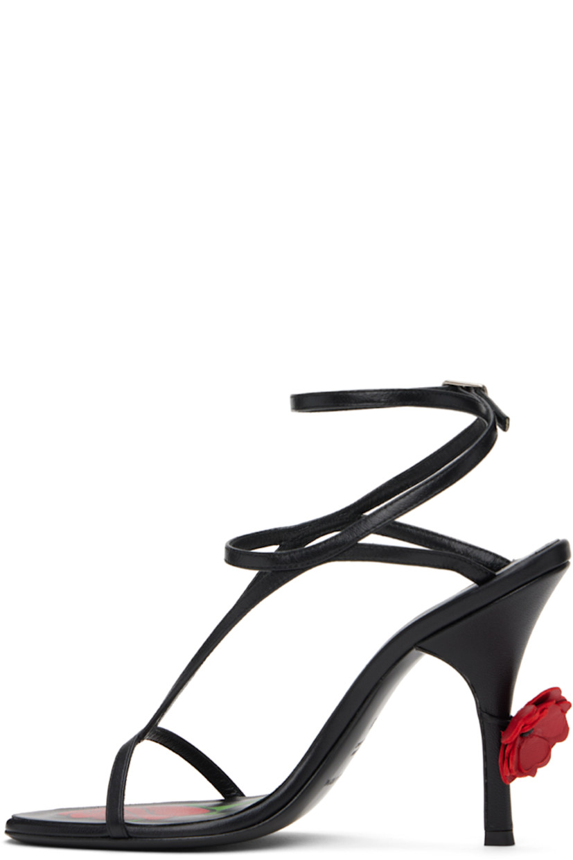 Patent calfskin heeled sandals in black.

· Open toe
· Straps at vamp
· Wraparound pin-buckle ankle strap
· Logo and graphic printed at calfskin footbed
· Floral appliqué at heel
· Covered stiletto heel with rubber injection
· Nubuck sole
· Heel: H4.25"

Supplier color: Black