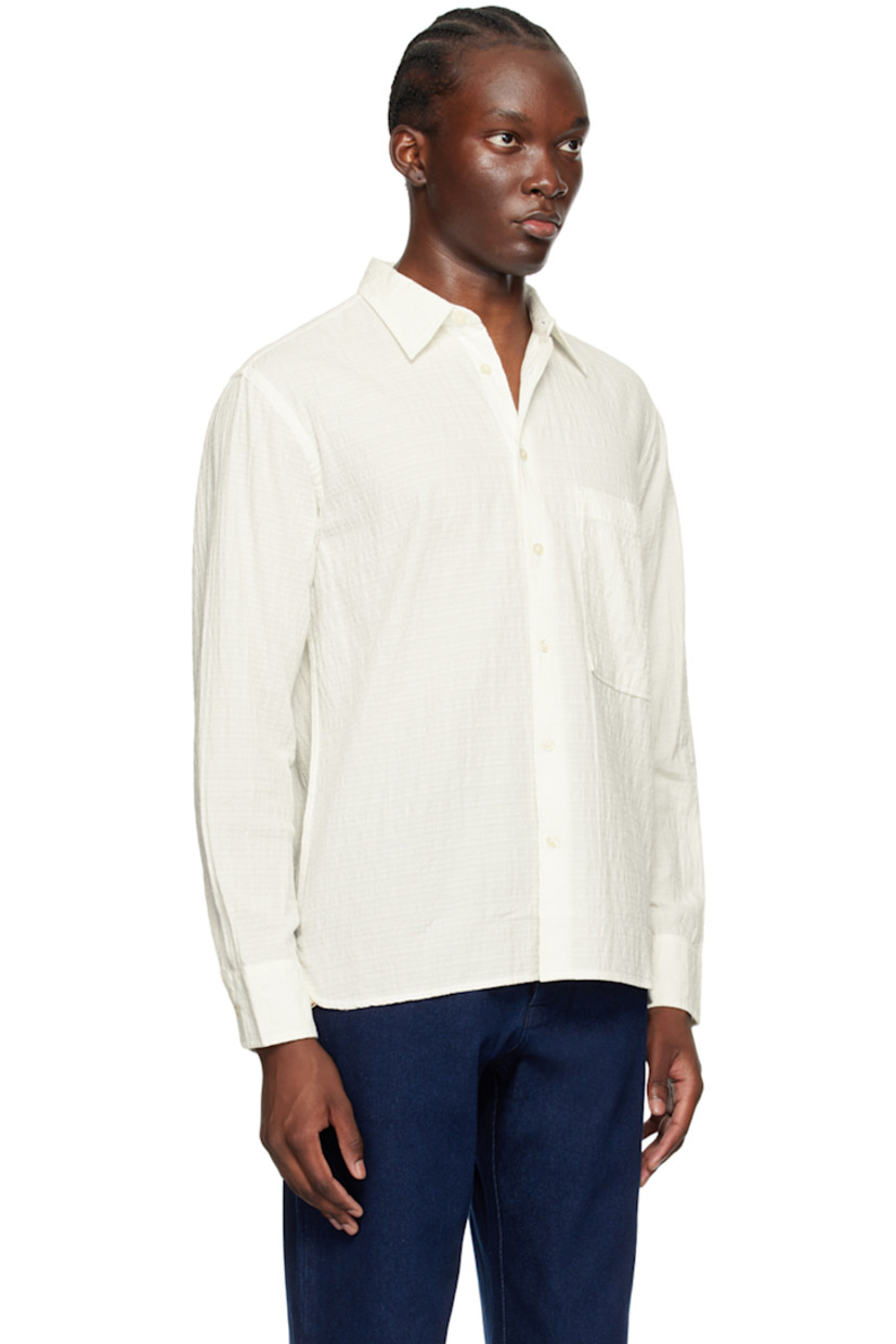 Organic cotton dobby cloth shirt.

· Spread collar
· Button closure
· Patch pocket at chest
· Droptail hem
· Adjustable single-button barrel cuffs
· Pleats at back yoke

Supplier color: Ecru