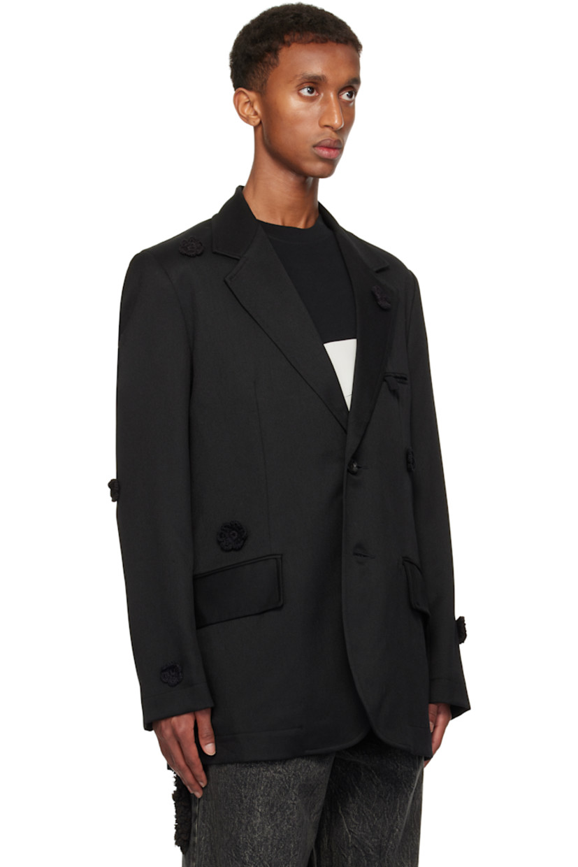 Wool drill blazer. Hand-woven cotton floral accents throughout.

· Notched lapel
· Button closure
· Welt pocket and flap pockets
· Padded shoulders
· Raw edge at sleeves and back
· Central vent at back hem
· Welt pockets at interior
· Full cupro satin lining

Supplier color: Black