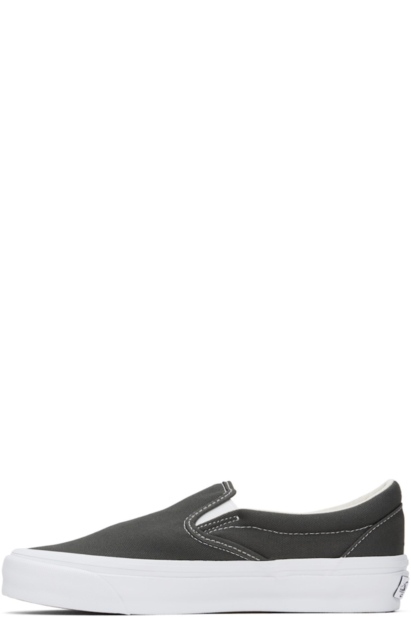 Low-top canvas slip-on sneakers in gray.

· Elasticized gussets at tongue
· Padded collar
· Logo flag at outer side
· Rubberized logo patch at heel
· Canvas lining
· Removable padded foam insole
· Treaded rubber sole
· Contrast stitching in white

Supplier color: Gunmetal