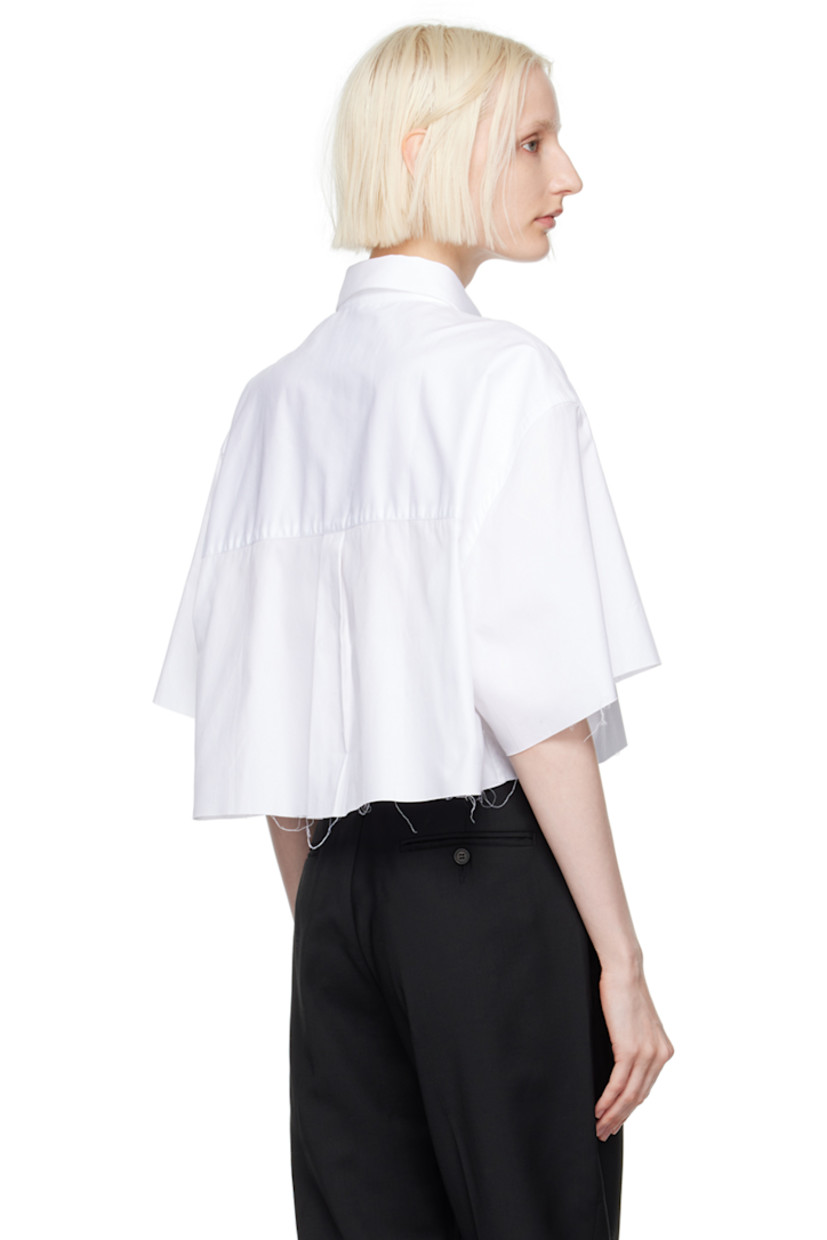 Oversized cotton twill shirt.

· Spread collar
· Button closure
· Logo embroidered at front
· Raw edge at cropped hem and cuffs
· Box pleat at back yoke

Supplier color: White