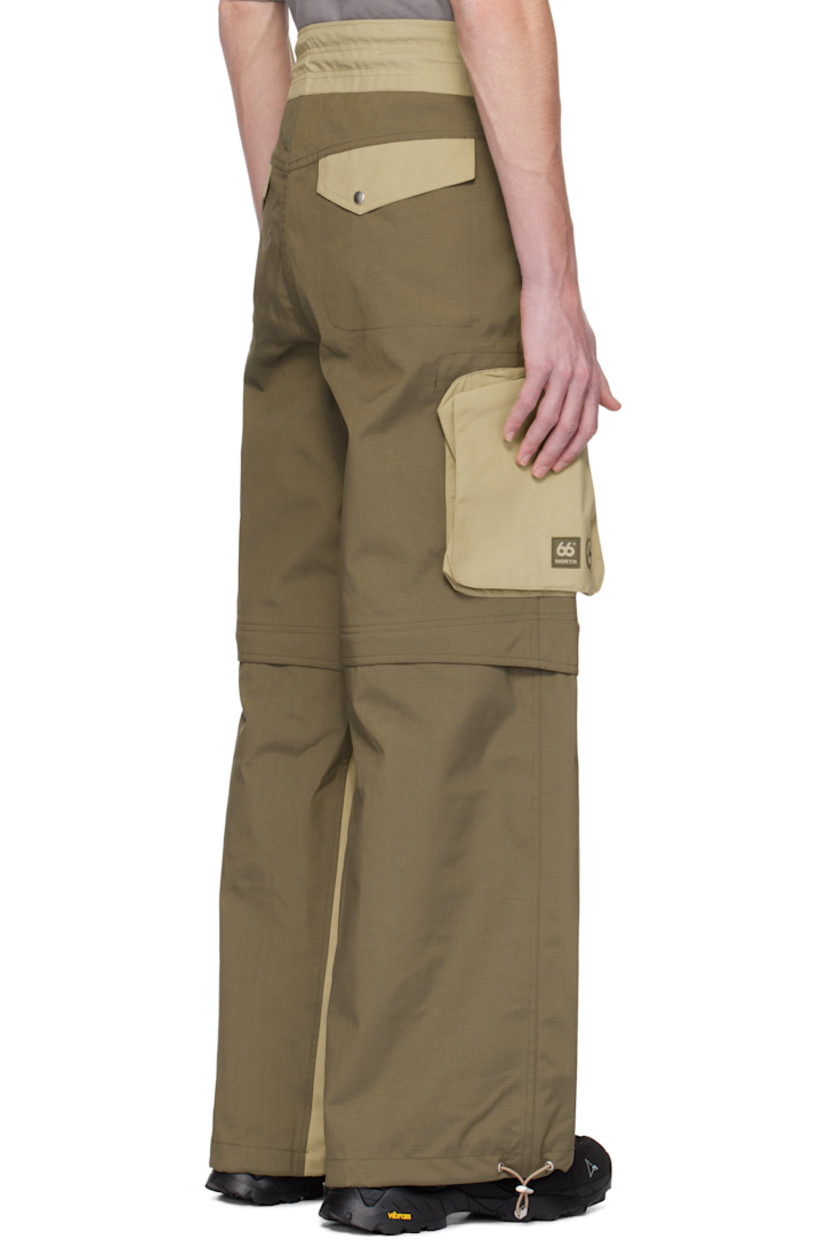 Loose-fit deadstock plain-woven stretch nylon cargo pants. Taped seams throughout.

· Water-resistant, breathable, and windproof
· Paneled construction
· Bungee-style drawstring at waistband and cuffs
· Four-pocket styling
· Zip fly
· Zip fastening at knees for shorts styling
· Zip bellows pocket at outseams
· Rubber logo patches at outseam

Part of the Charlie Constantinou x 66°North collaboration.

Supplier color: Earth