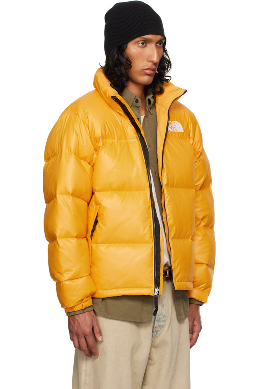 RDS-certified down-filled and quilted non-PFC DWR-coated recycled nylon ripstop jacket. Windproof, water-repellent, and abrasion-resistant.

· Packable
· Stowaway hood at funnel neck
· Concealed bungee-style drawstring at hood and hem
· Zip closure
· Logo embroidered at chest and back
· Zip pockets
· Packs into zip pocket
· Text embroidered at sleeve
· Velcro fastening at elasticized cuffs
· Triclimate® press-stud fastening at cuffs
· Zip pocket at interior
· Full nylon taffeta lining

Available exclusively at SSENSE.

Supplier color: Summit gold shine

Fill: 85% down, 15% waterfowl feathers.
