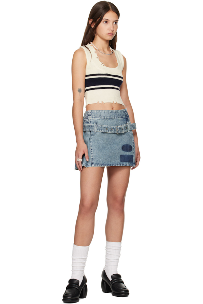 Non-stretch denim miniskirt. Fading throughout. 

· Asymmetrical construction
· Belt loops and detachable pin-buckle belt 
· Printed patches at front hem
· Knife pleats at side and back 
· Logo embroidered at back waistband

Supplier color: Blue