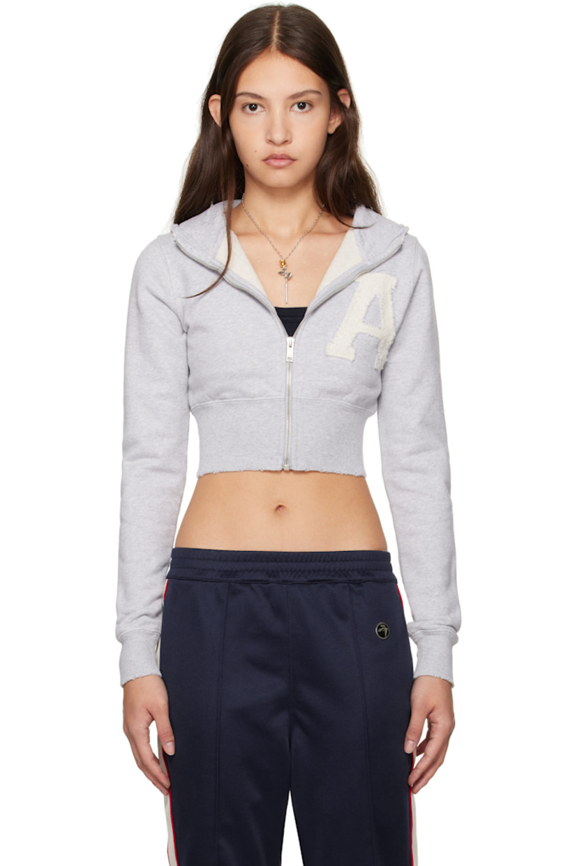 Organic cotton French terry hoodie. 

· Distressing at hood, hem, and cuffs
· Zip closure
· Reverse French terry logo appliqué at front
· Rib-knit cropped hem and cuffs

Supplier color: Grey melange