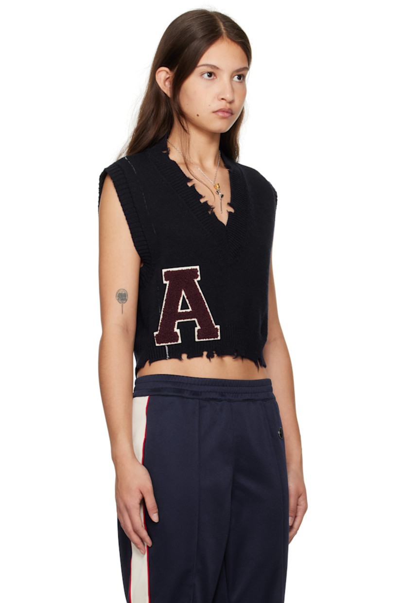 Knit virgin wool vest.

· Distressing at rib-knit V-neck and cropped hem
· Bouclé logo appliqué at front
· Whipstitching at front and back
· Rib-knit armscyes

Supplier color: Navy russet brown