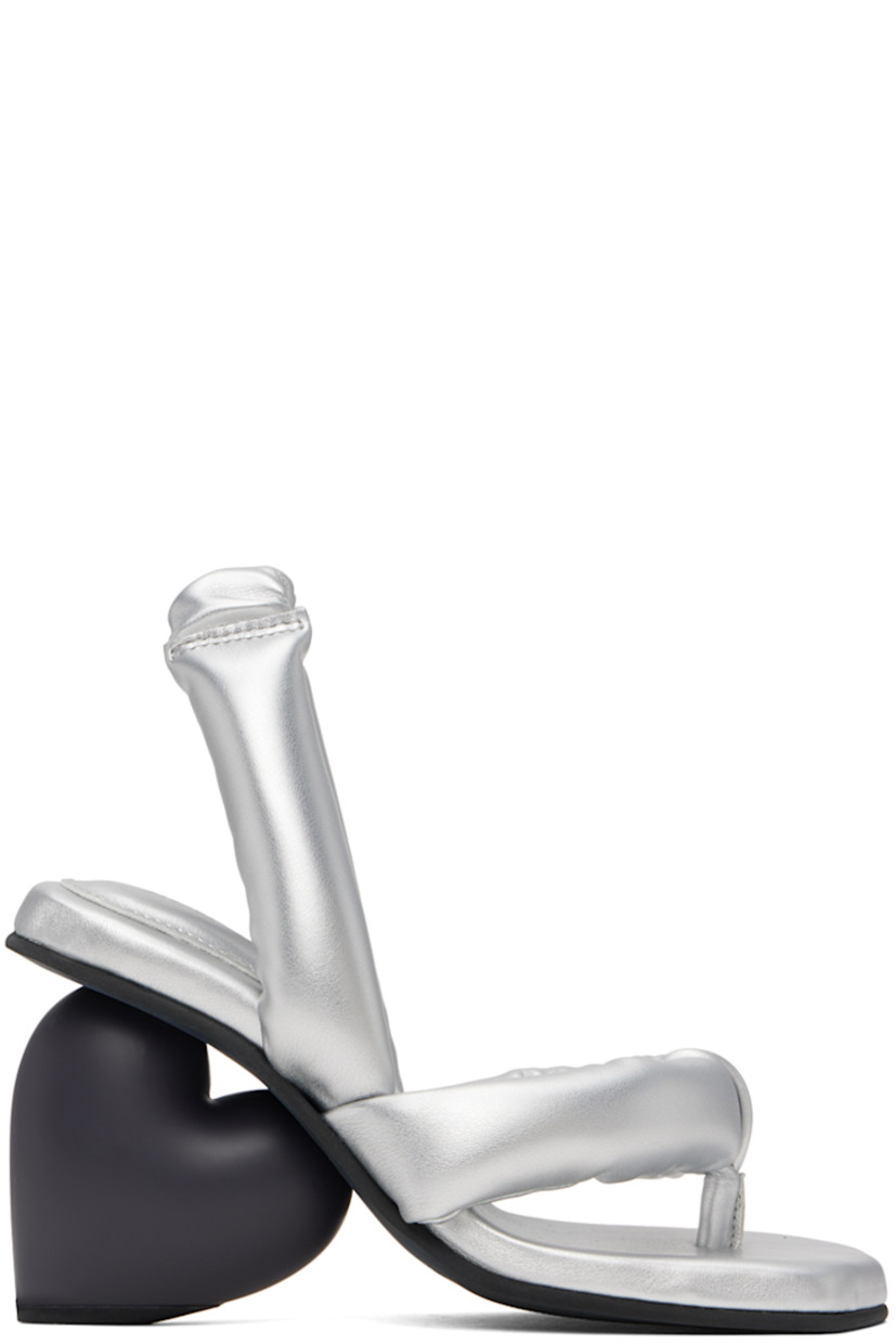 Padded buffed faux-leather heeled sandals in metallic silver tone. 

· Open square toe
· Thong-style strap at vamp
· Partially elasticized slingback strap 
· Logo embossed at padded footbed
· Sculptural heel with rubber injection
· Treaded rubber sole
· Heel: H3.25"

Supplier color: Silver vegan leather