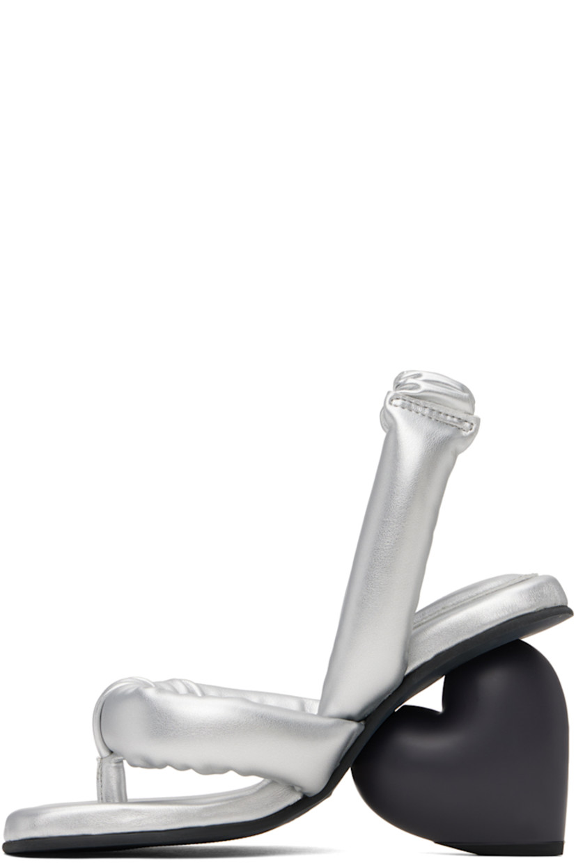 Padded buffed faux-leather heeled sandals in metallic silver tone. 

· Open square toe
· Thong-style strap at vamp
· Partially elasticized slingback strap 
· Logo embossed at padded footbed
· Sculptural heel with rubber injection
· Treaded rubber sole
· Heel: H3.25"

Supplier color: Silver vegan leather