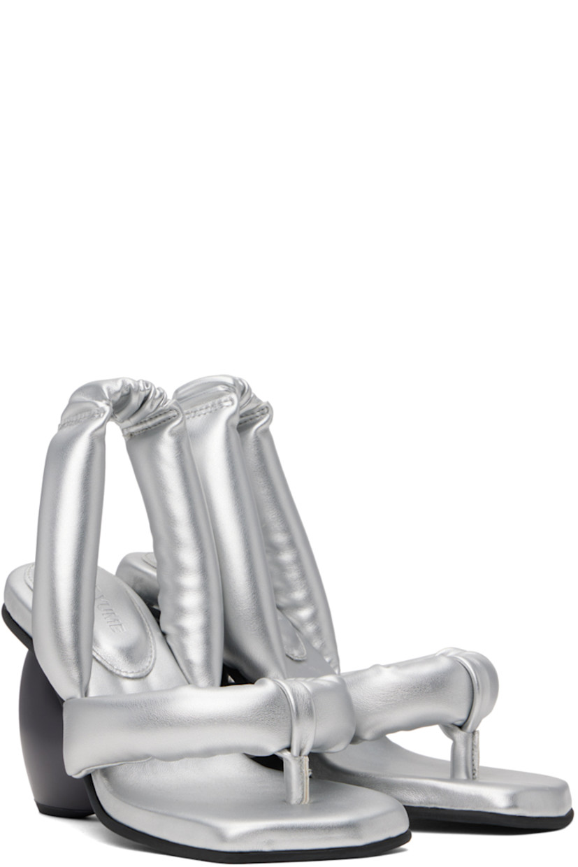 Padded buffed faux-leather heeled sandals in metallic silver tone. 

· Open square toe
· Thong-style strap at vamp
· Partially elasticized slingback strap 
· Logo embossed at padded footbed
· Sculptural heel with rubber injection
· Treaded rubber sole
· Heel: H3.25"

Supplier color: Silver vegan leather