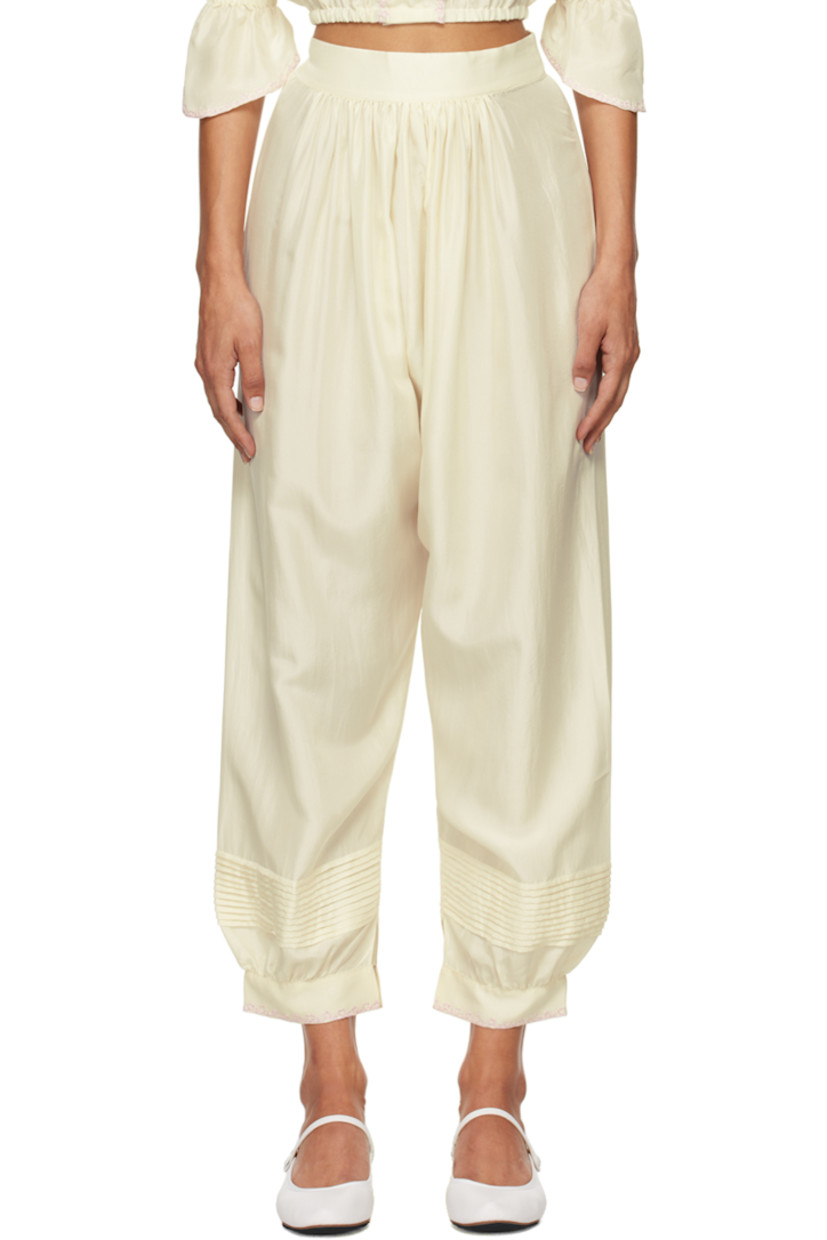 Silk satin trousers. 

· Gathering at elasticized waistband
· Pintucks at legs
· Embroidered detailing at vented cuffs
· Button fastening and cutout at outseam

Supplier color: Ecru