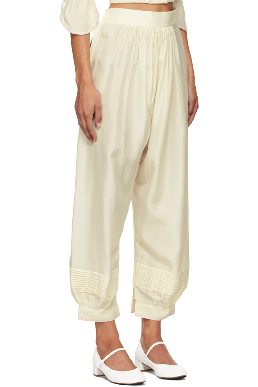 Silk satin trousers. 

· Gathering at elasticized waistband
· Pintucks at legs
· Embroidered detailing at vented cuffs
· Button fastening and cutout at outseam

Supplier color: Ecru