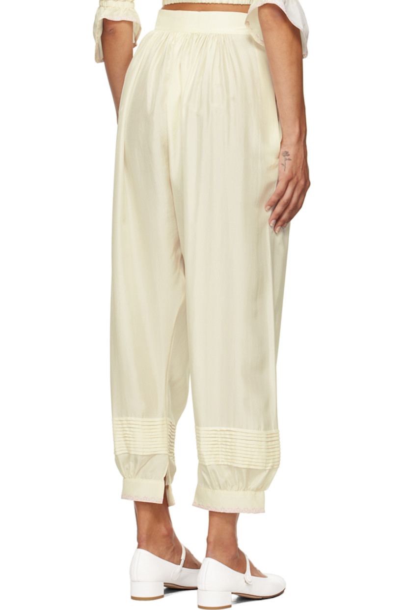 Silk satin trousers. 

· Gathering at elasticized waistband
· Pintucks at legs
· Embroidered detailing at vented cuffs
· Button fastening and cutout at outseam

Supplier color: Ecru