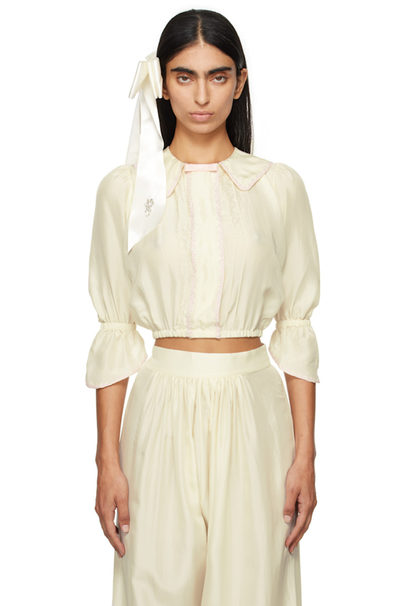 Silk satin blouse. Embroidered detailing throughout.

· Grosgrain bow at spread collar
· Concealed press-stud closure
· Pinched seams at front 
· Elasticized hem and flared cuffs
· Balloon sleeves 

Supplier color: Ecru