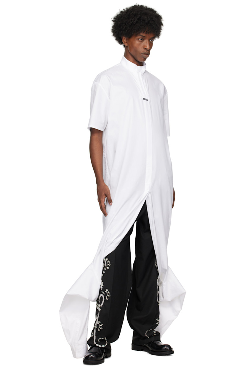Poplin cotton shirt.

· Layered construction
· Short sleeves
· Rib-knit stand collar with half-zip placket
· Logo patch at chest
· Single-piece bodice
· Integrated long-sleeve shirt overlay
· Button-down spread collar at overlay
· Button placket and barrel cuffs
· Box pleat at back

Supplier color: White