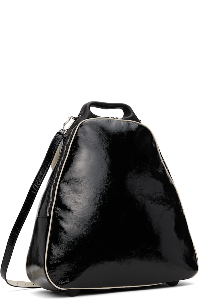 Patent grained leather top handle bag in black. 

· Piping throughout 
· Rigid leather carry handle
· Adjustable and detachable crossbody strap
· Flap with patch pocket at face 
· Rubberized bumper studs at base 
· Two-way zip closure 
· Patch pocket at interior 
· Twill lining
· H15.25" x W15" x D6.25"
· Total height: H17.25"

Part of the ECCO.kollektive x Kiko Kostadinov collaboration.

Supplier color: Black/Whitecap gray